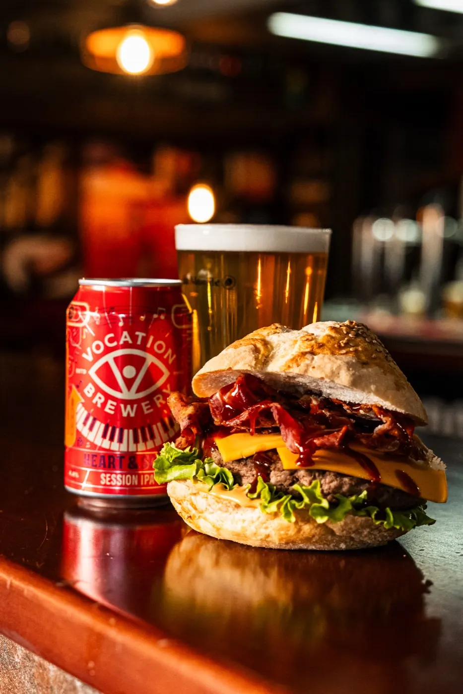 Hamburger con bacon e cheddar accanto a una pinta di birra sul bancone